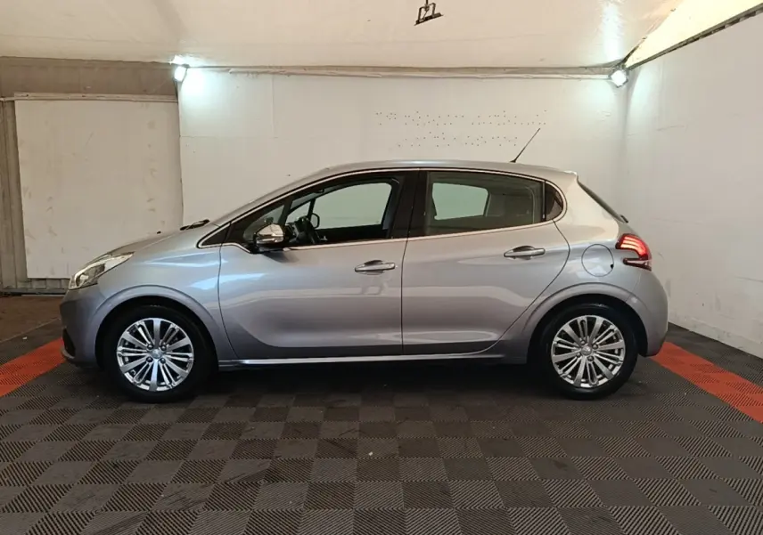 Peugeot 208 Puretech 82 Allure gris clair vue de profil côté gauche dans un garage éclairé.