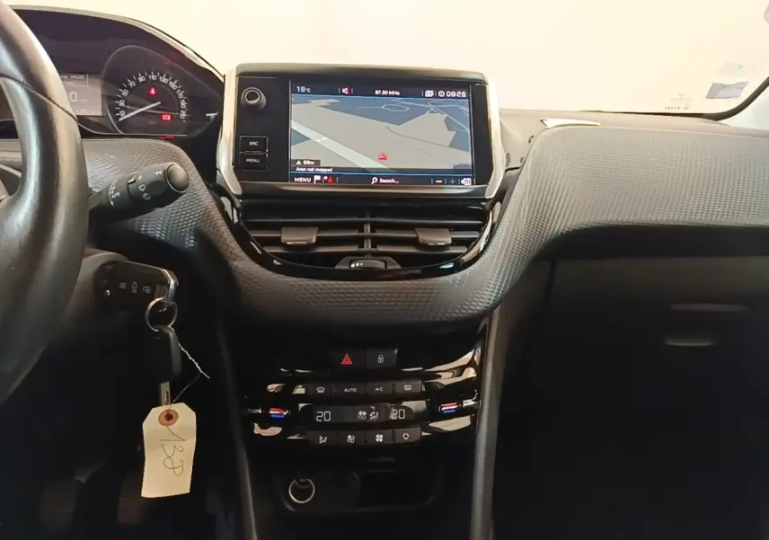 Vue intérieure centrée sur la console tactile et le tableau de bord de la Peugeot 208 gris clair, version Puretech 82 Allure.