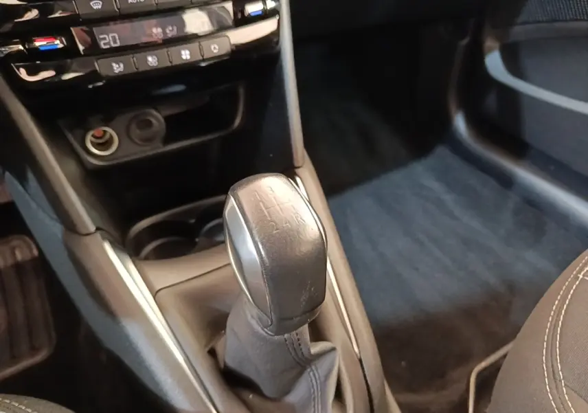 Gros plan sur le levier de vitesses manuel noir de la Peugeot 208 Puretech 82 Allure, intérieur gris foncé.