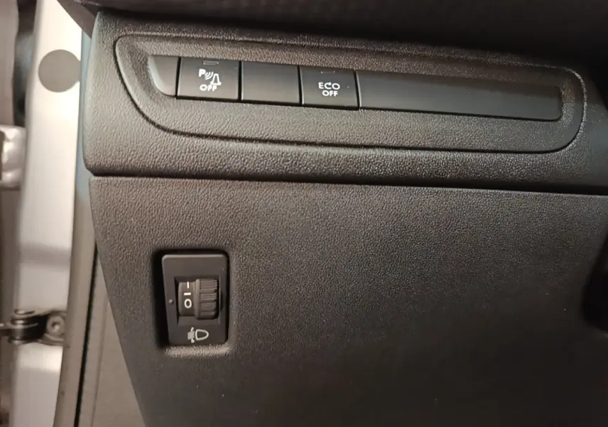 Détail intérieur montrant les commandes de désactivation du radar de recul et d'activation Eco sur Peugeot 208 gris clair.