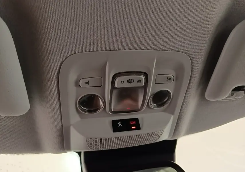 Vue intérieure du plafonnier de la Peugeot 208 gris clair, avec commandes d’éclairage et bouton SOS éclairé rouge.
