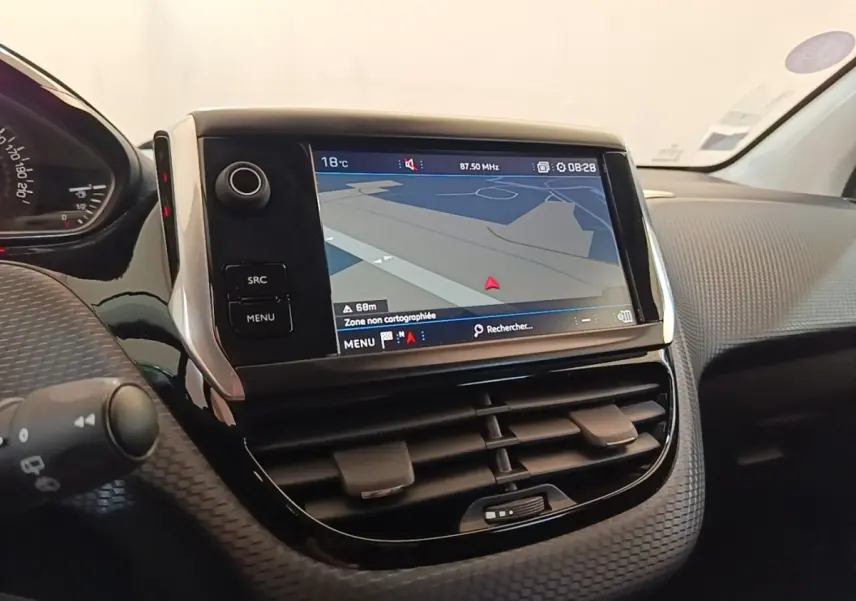 Gros plan sur l’écran tactile central et la console noire texturée du tableau de bord de la Peugeot 208 gris clair.