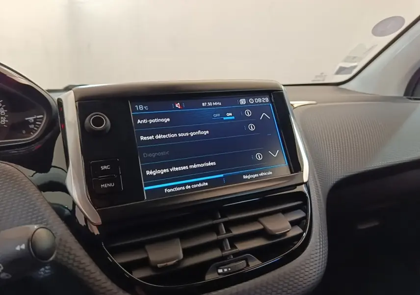 Vue intérieure du tableau de bord de la Peugeot 208 gris clair, avec écran tactile affichant les réglages d'anti-patinage.