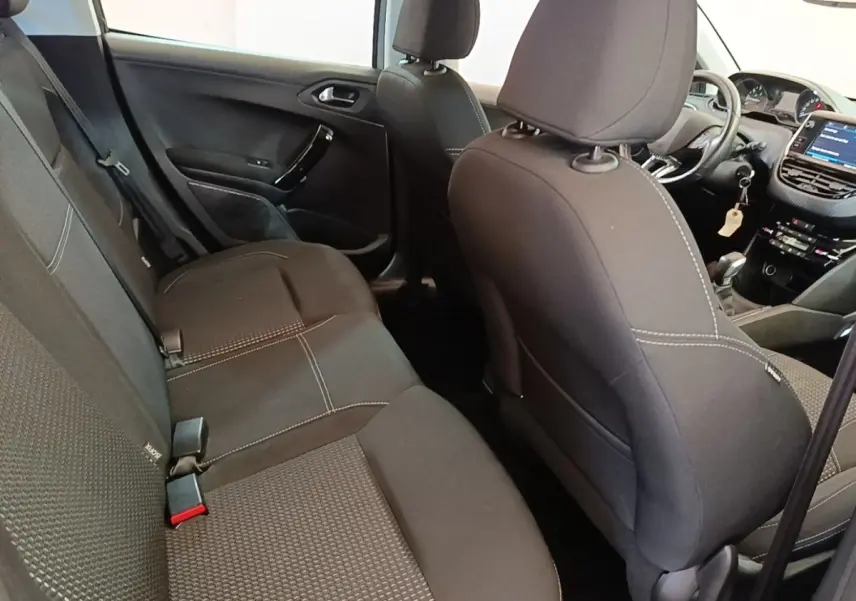 Vue intérieure arrière droite de la Peugeot 208 Puretech 82 Allure 2019, sièges tissu noirs avec surpiqûres blanches.