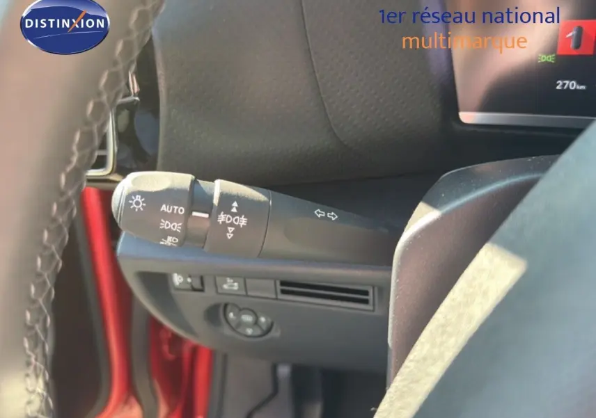 Gros plan sur la commande des feux et clignotants à gauche du volant d'une Citroën C4 X rouge Elixir Metal.