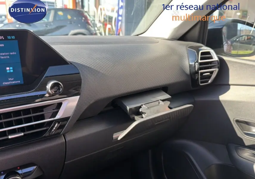 Vue intérieure côté passager du tableau de bord noir du Citroën C4 X 2023 avec boîte à gants ouverte.