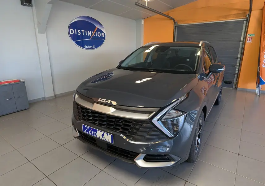 KIA SPORTAGE MY25 gris eclipse en 3/4 avant droit dans un showroom avec calandre noire et phares LED distinctifs.