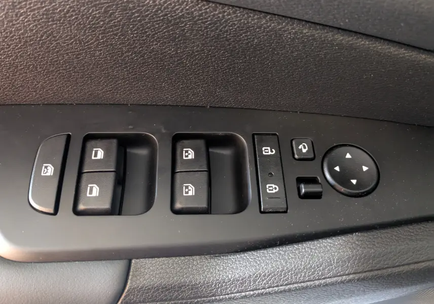 Panneau de commandes des vitres et rétroviseurs côté conducteur du Kia Sportage gris eclipse MY25, intérieur noir.