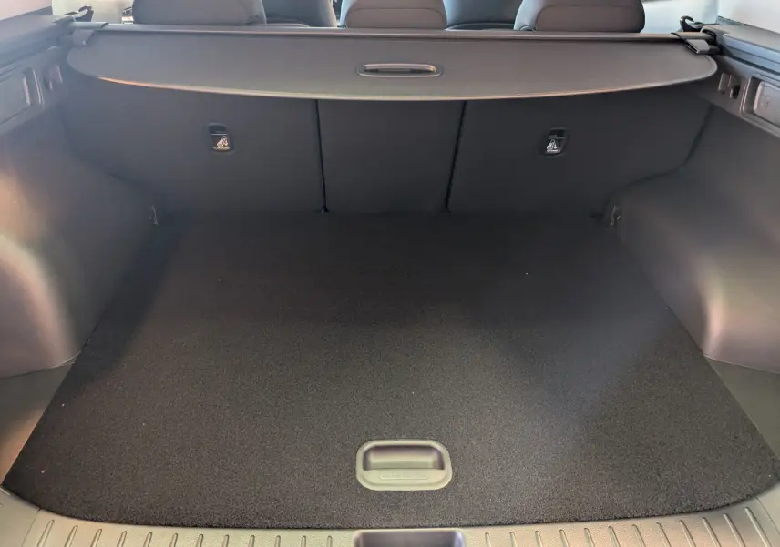 Coffre spacieux et propre du Kia Sportage MY25 gris eclipse, vu de l'arrière avec cache-bagages en place.
