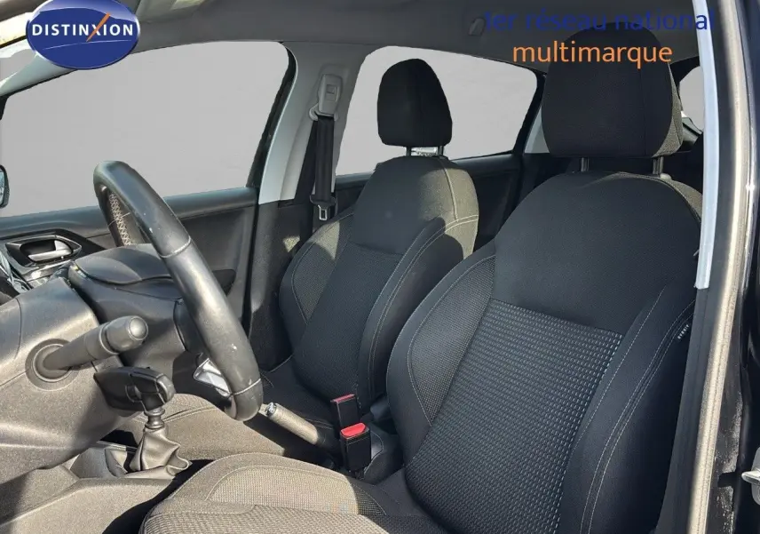 Intérieur avant de la Peugeot 208 noire perle métal, vue côté conducteur montrant les sièges et le volant.