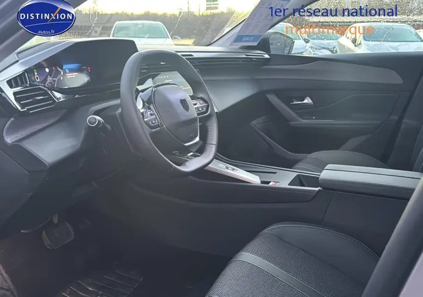 Vue intérieure côté conducteur de la Peugeot 308 gris artense 2025, avec tableau de bord numérique et volant multifonction.
