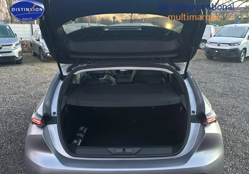 Vue arrière ouverte sur coffre spacieux d'une Peugeot 308 1.2 hybrid 145 allure gris artense avec feux arrière LED allumés.