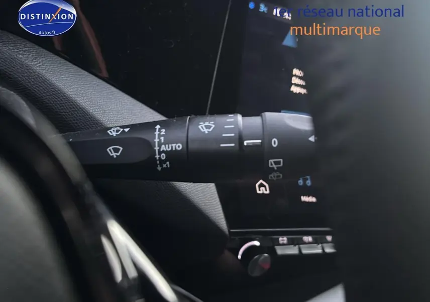 Gros plan sur la commande des essuie-glaces à gauche du volant dans l'habitacle gris d'une Peugeot 308 2025.