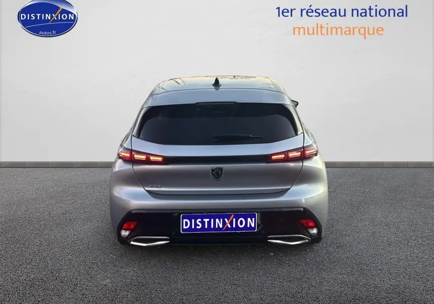 Vue arrière d'une Peugeot 308 gris artense 2025 avec feux arrière LED allumés sur fond neutre.