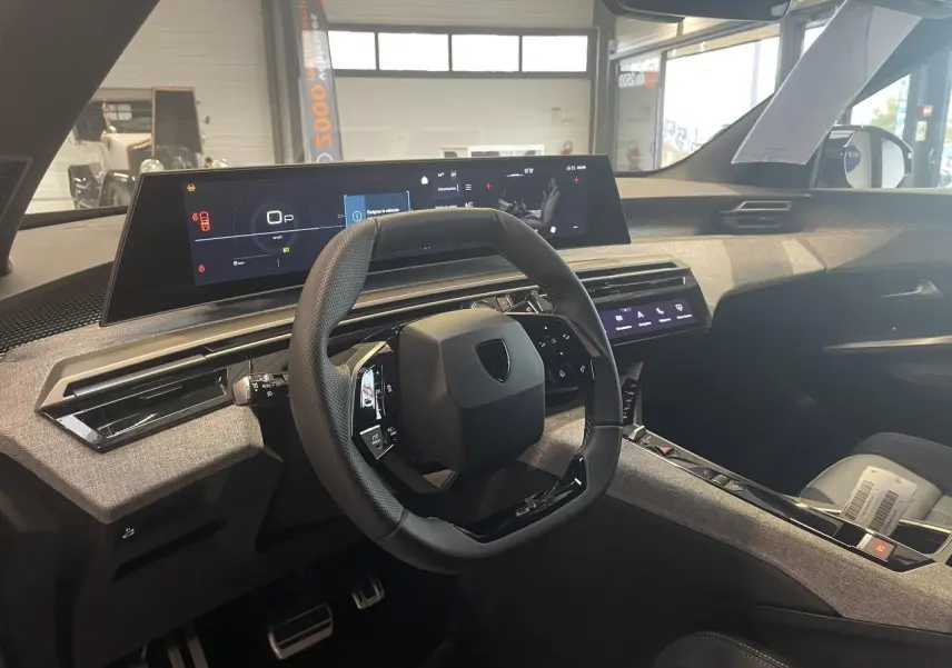 Vue intérieure côté conducteur du Peugeot 3008 GT 2025, volant compact noir et tableau de bord numérique panoramique.