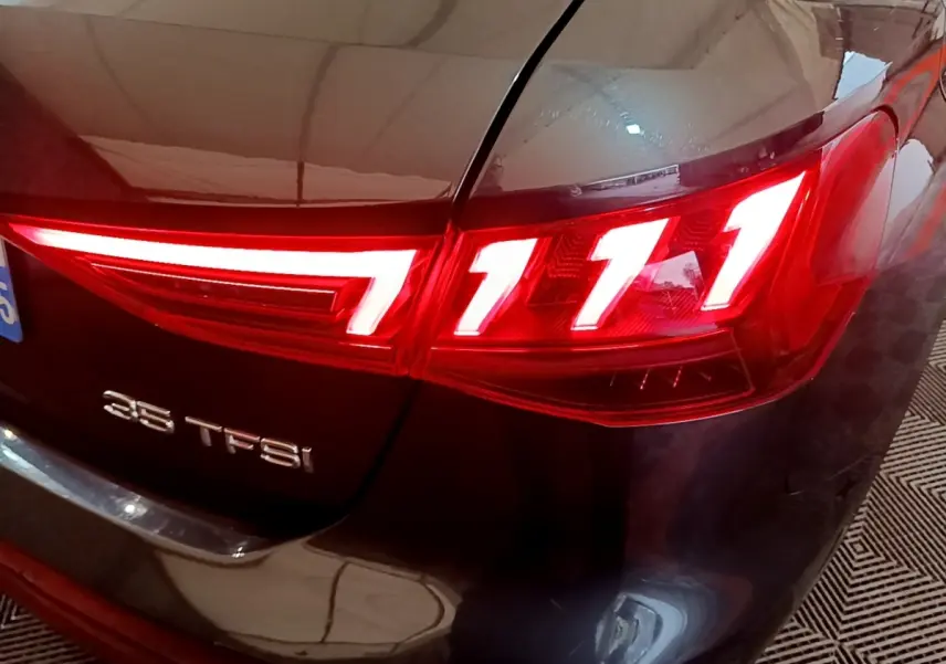 Gros plan sur le feu arrière droit rouge allumé de l'Audi A3 gris foncé avec l'inscription 35 TFSI sur le coffre.