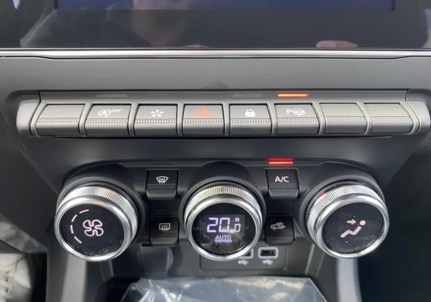 Gros plan sur la console centrale du Renault Arkana 2022, boutons de climatisation et commandes en ligne horizontale.