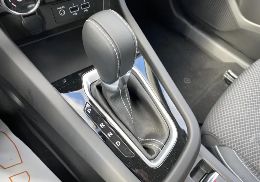 Gros plan sur le levier de vitesses automatique noir avec surpiqûres blanches dans une Renault Arkana 2022.