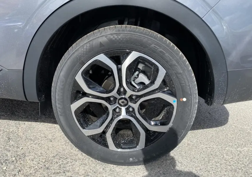 Gros plan sur la roue avant droite d’un Renault Arkana gris foncé, avec jante alliage noire et argentée au design moderne.