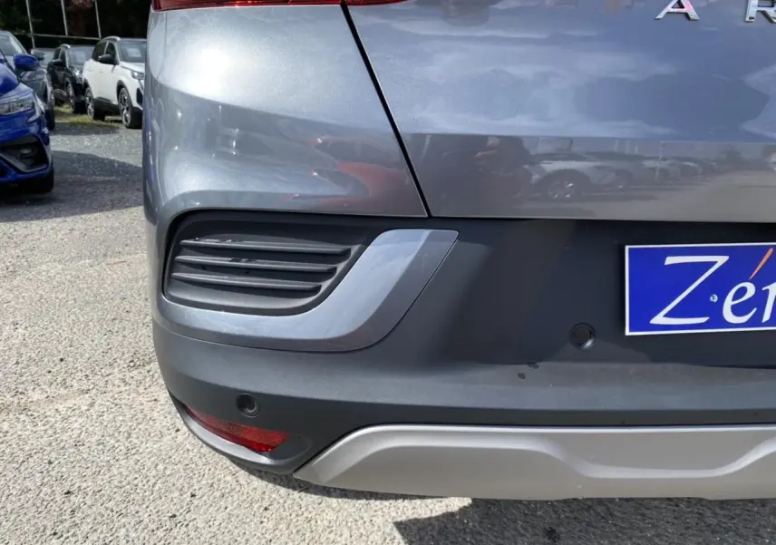 Gros plan sur le coin arrière droit d’un Renault Arkana gris foncé, avec feu arrière et capteurs de recul visibles.