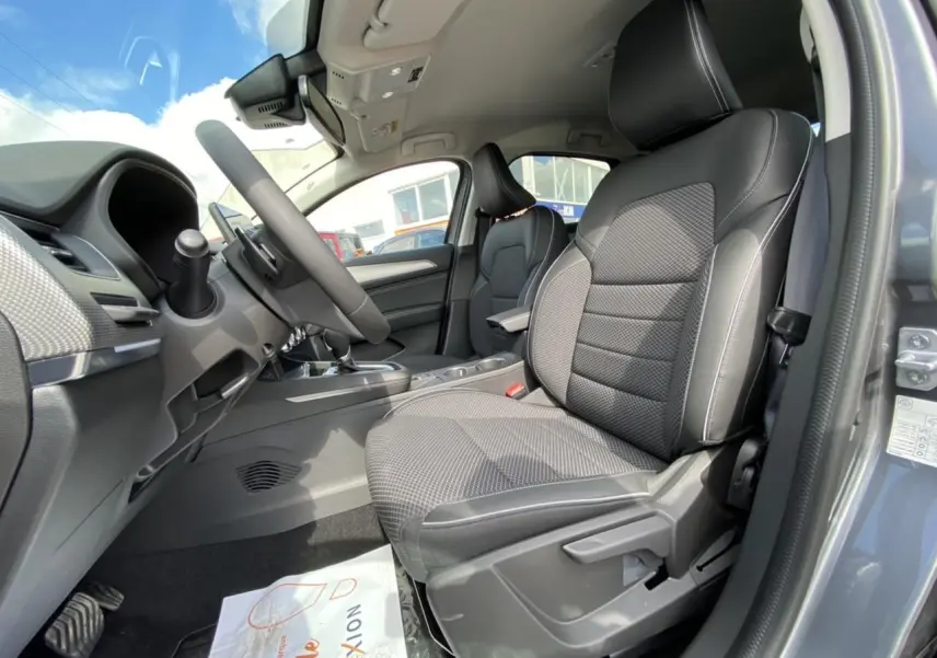 Vue intérieure côté conducteur du Renault Arkana gris foncé 2022, mettant en valeur les sièges et le volant.