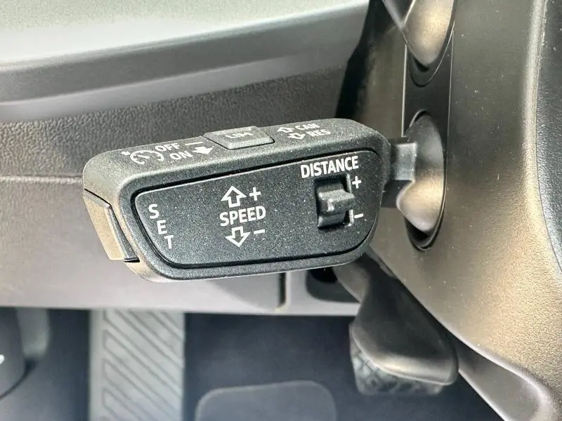 Gros plan sur la commande noire du régulateur de vitesse avec réglages de vitesse et distance dans un Audi A3 Sportback 2024.