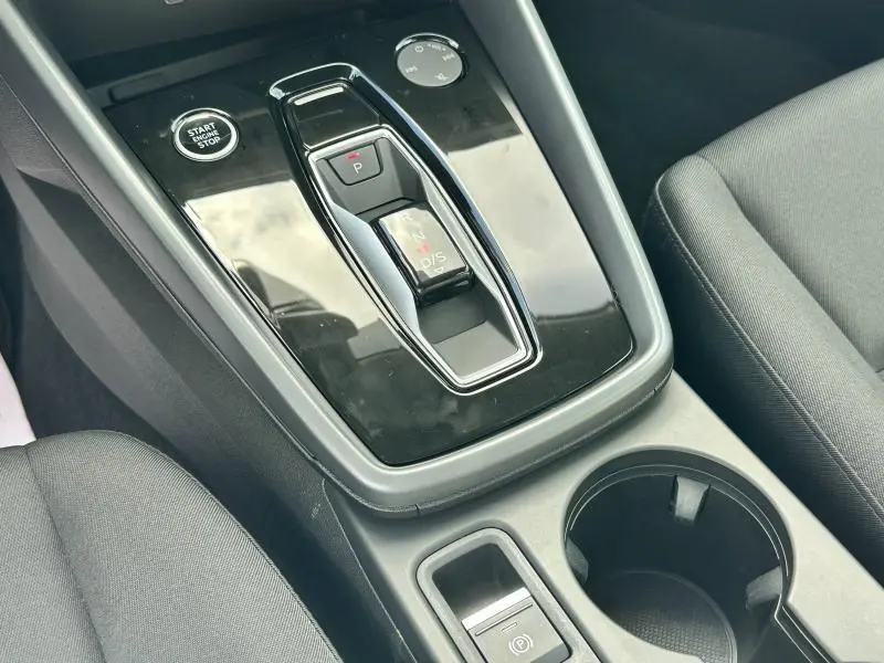 Vue rapprochée de la console centrale noire de l'Audi A3 Sportback 2024 avec levier de vitesse automatique et bouton start/stop.