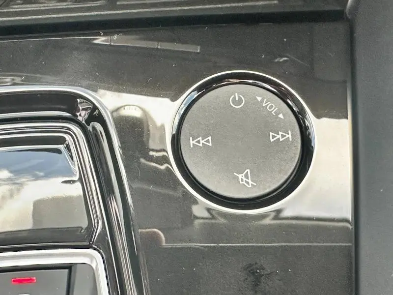 Gros plan sur la molette de volume noire brillante avec commandes audio sur la console centrale de l'Audi A3 Sportback 2024.