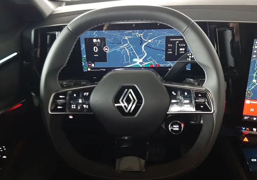 Vue rapprochée du volant noir du Renault Austral 2025 avec écran numérique affichant la navigation.