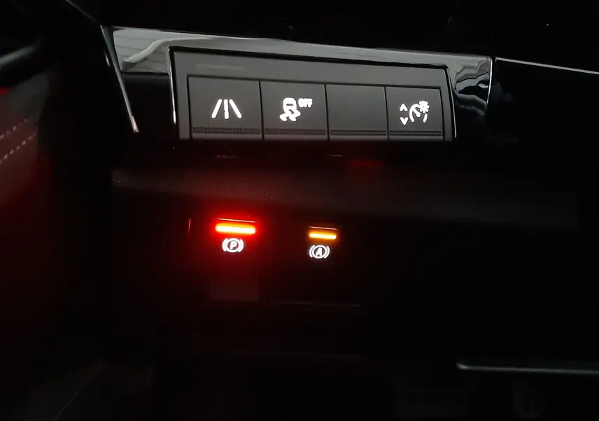 Gros plan sur les commandes d’assistance et frein électronique du tableau de bord du Renault Austral gris schiste satin.
