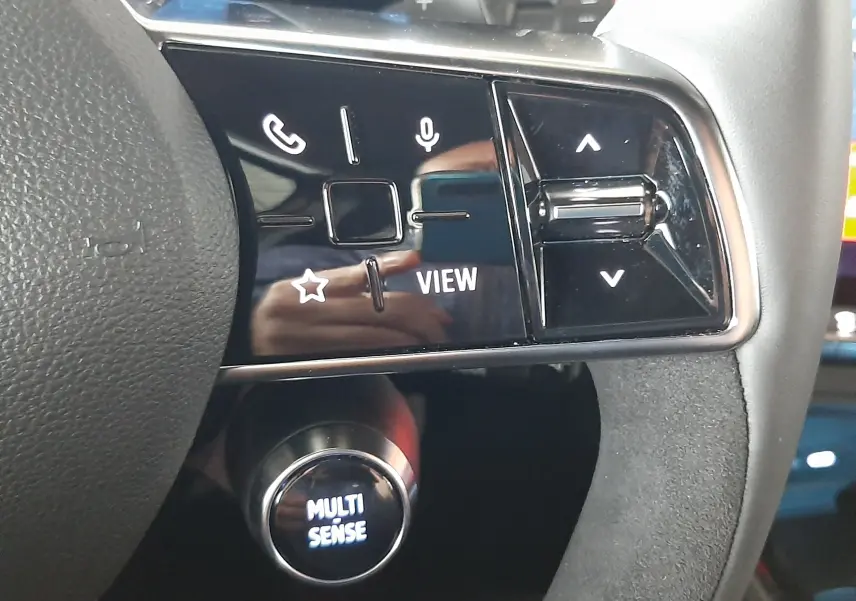 Gros plan sur les commandes au volant noir brillant du Renault Austral E-Tech hybride 2025, avec bouton Multi Sense éclairé.