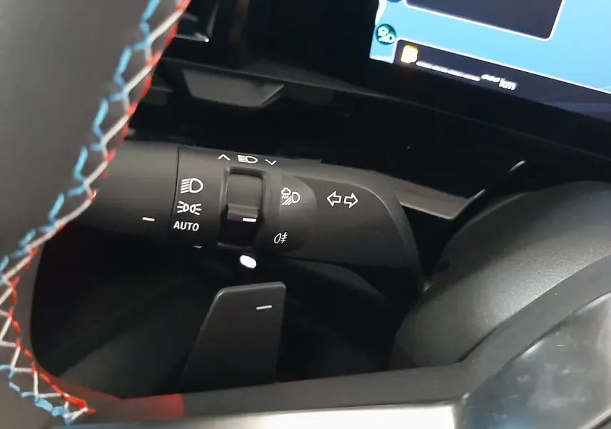 Détail du commodo d'éclairage et clignotants côté gauche sur Renault Austral gris schiste satin, intérieur noir avec volant surpiqué.