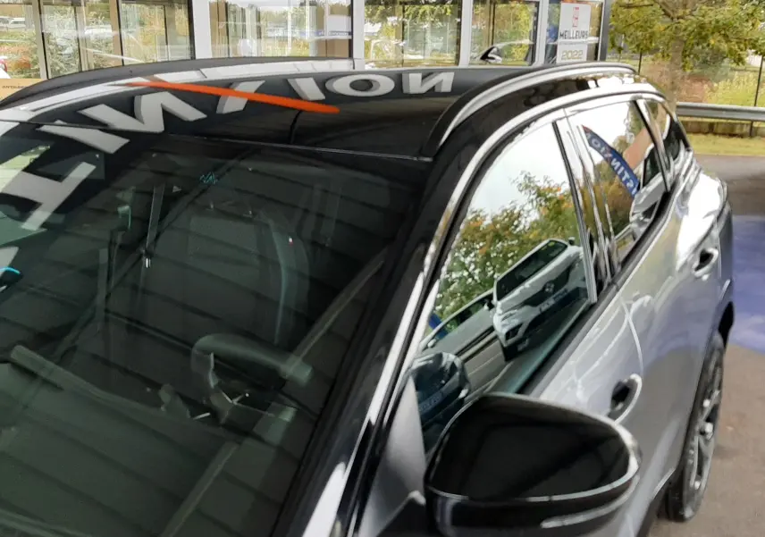 Vue 3/4 avant droit du Renault Austral gris schiste satin avec toit noir brillant et rétroviseur assorti.