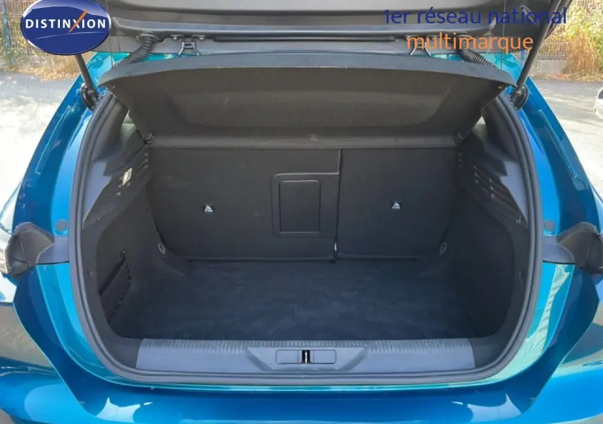 Coffre ouvert vu de l'arrière d'une Peugeot 308 2024 bleu obsession métal, montrant un espace de rangement vide.