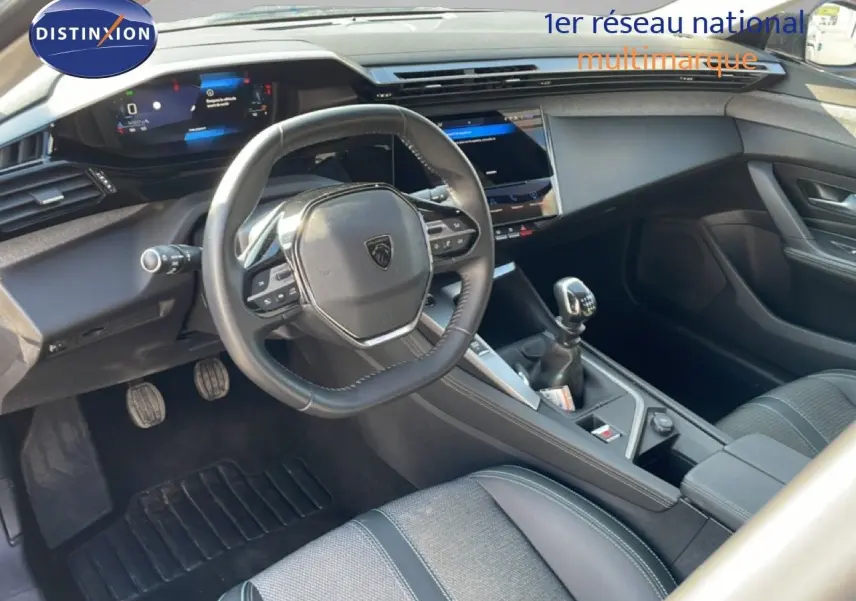 Vue intérieure côté conducteur de la Peugeot 308 2024, volant cuir multifonction et levier de vitesse manuelle visibles.