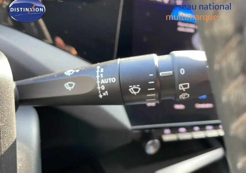 Gros plan sur la commande d’essuie-glace à gauche du volant dans l’habitacle d’une Peugeot 308 bleu obsession métal 2024.
