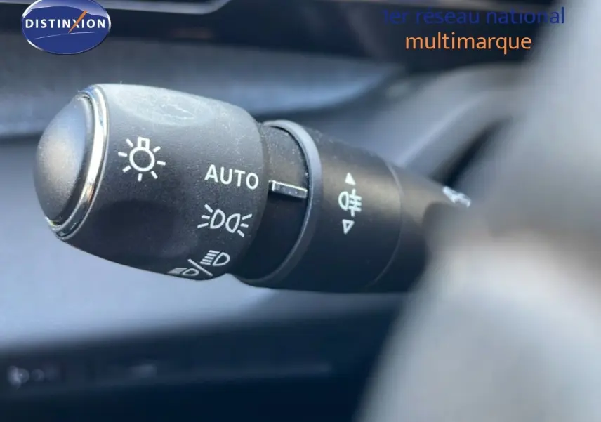 Gros plan sur la commande des feux automatiques dans l’habitacle d’une Peugeot 308 Bleu Obsession 2024.