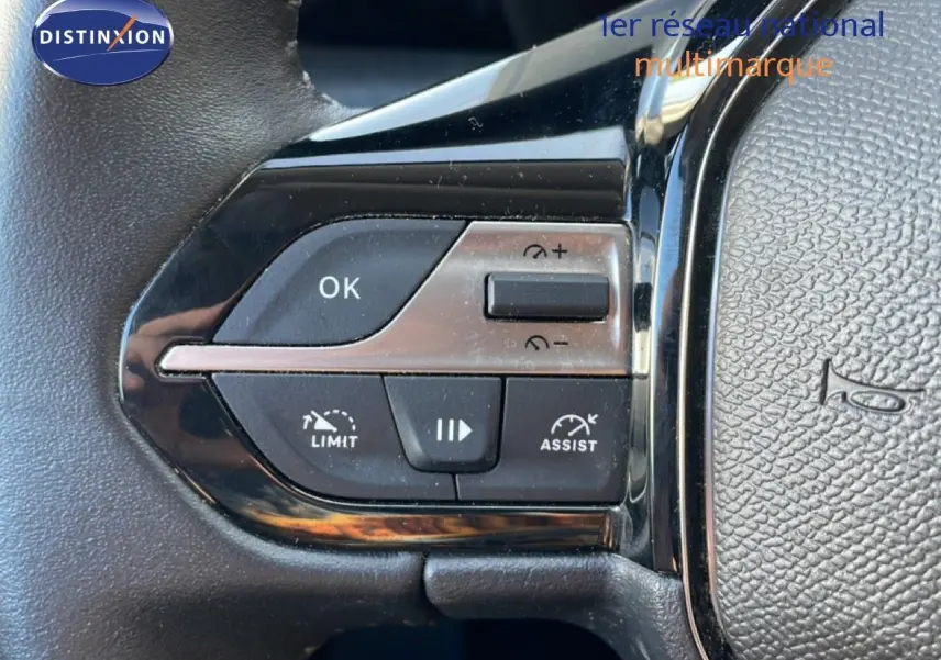 Gros plan sur les commandes au volant de la Peugeot 308 2024, boutons noirs et chrome avec fonctions limiteur et assist.