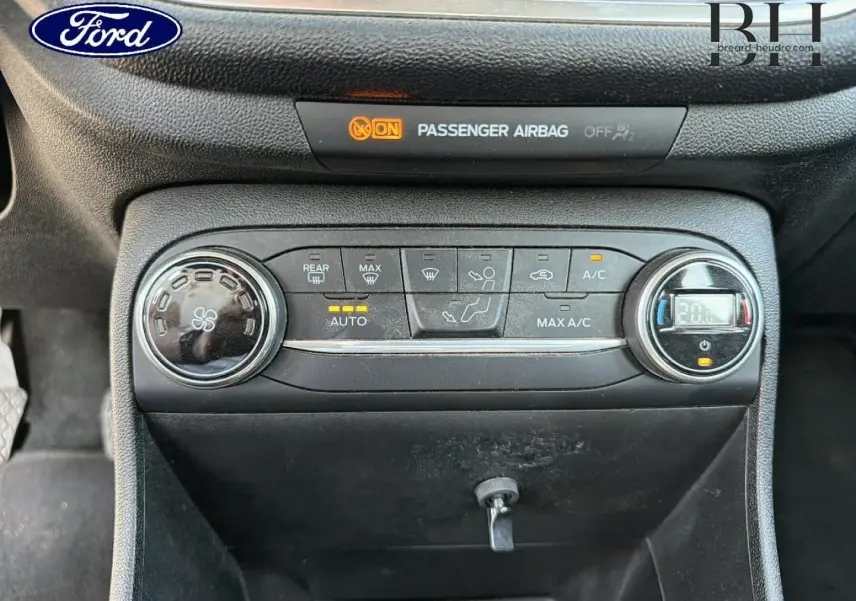 Vue rapprochée de la console centrale de la Ford Fiesta 2018, avec commandes climatisation et témoin airbag passager allumé.