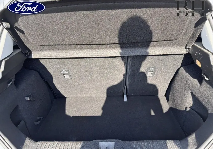 Coffre ouvert de la Ford Fiesta blanc glacier, vue de l'intérieur montrant l'espace de chargement et la banquette arrière rabattable.