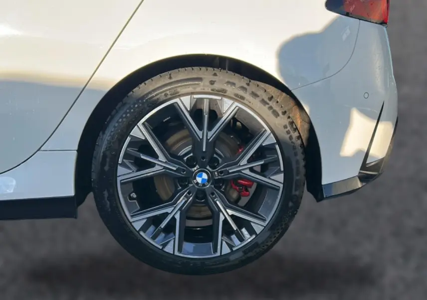 Gros plan sur la jante 18 pouces bicolore en Y d’une BMW Série 1 blanche alpine, avec étrier de frein rouge visible à l’arrière.