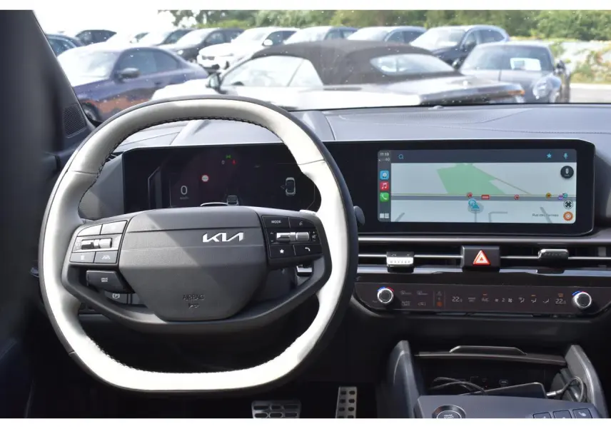 Vue intérieure centrée sur le volant noir et blanc du Kia Sportage 2026 avec écran tactile et navigation affichée.