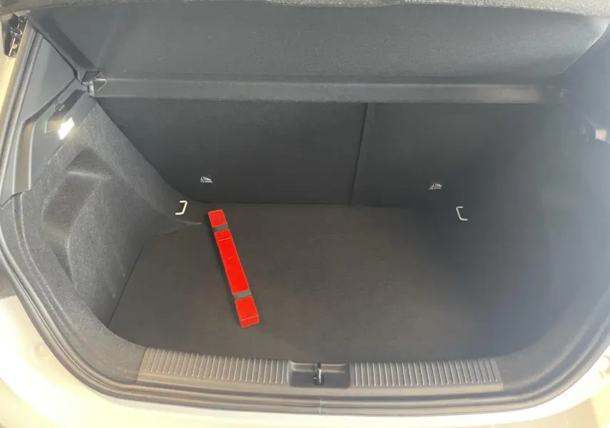 Coffre ouvert vu de face d'une MG3 blanche, avec intérieur noir et triangle de signalisation rouge posé au sol.