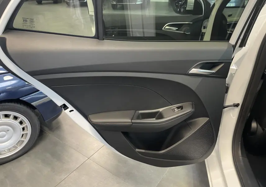 Vue intérieure de la porte arrière gauche blanche du MG3 1.5 Hybrid+ Luxury avec accoudoir et commande de vitre.