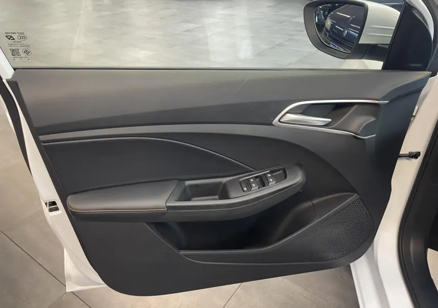 Vue intérieure côté gauche de la porte avant blanche du MG3 1.5 Hybrid+ avec commandes de vitres et poignée argentée.