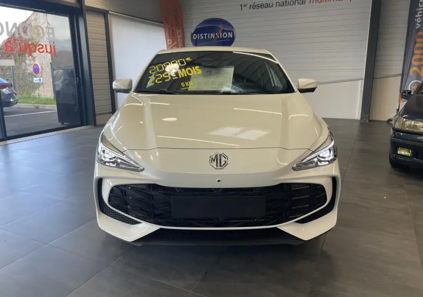 Vue avant d'une MG3 1.5 Hybrid+ blanche avec calandre noire et phares LED allumés en showroom.