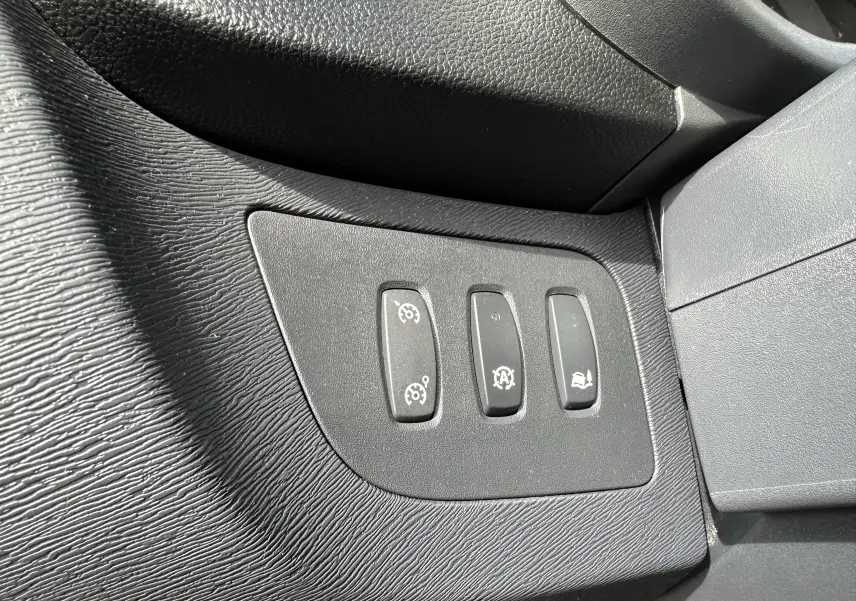 Gros plan sur les trois boutons de commande du tableau de bord intérieur noir du Nissan NV250 blanc, version 2020.