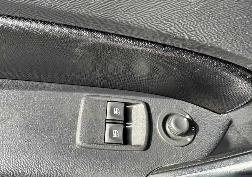 Commandes électriques des vitres et réglage des rétroviseurs sur la porte côté gauche d'un Nissan NV250 blanc 2020