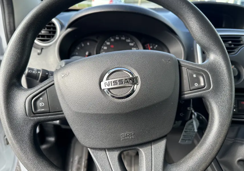 Vue rapprochée du volant noir avec logo Nissan au centre du tableau de bord du NV250 blanc de 2020.