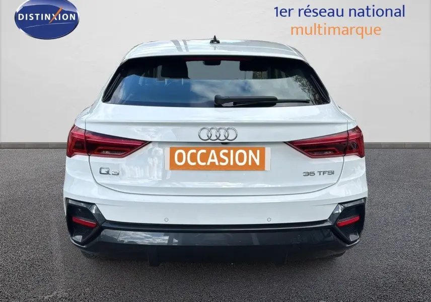 Vue arrière d'un Audi Q3 Sportback blanc de 2021 avec feux rouges et logo Audi bien visibles.